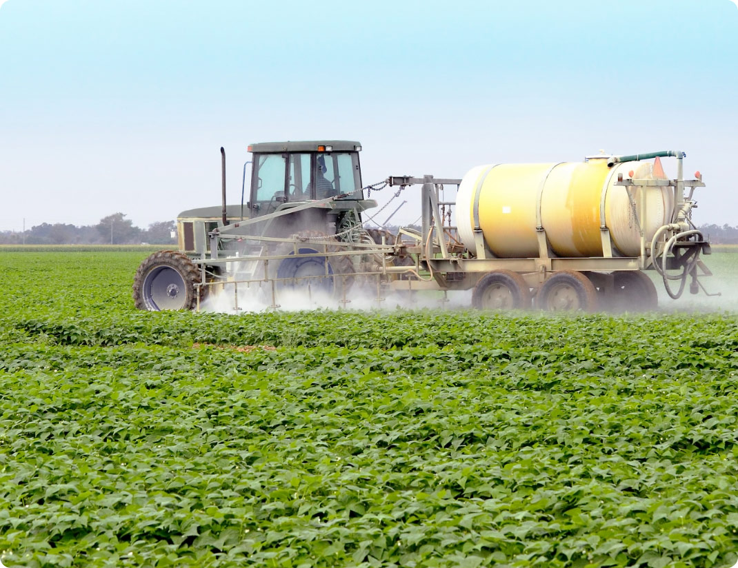 Tractor pulling spraying equipment in a crop field